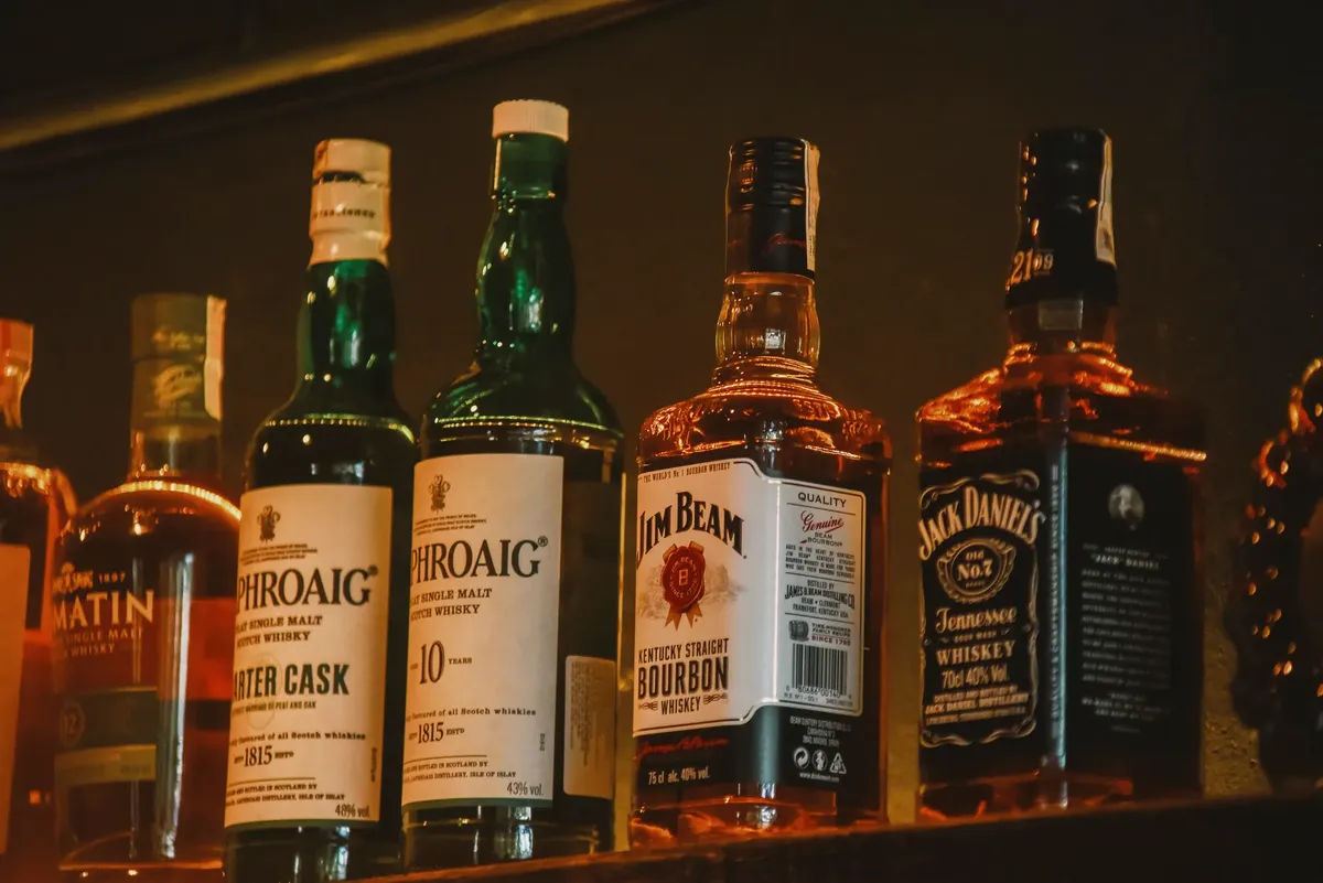 A selection of premium whiskey brands elegantly arranged on a dimly lit display shelf.